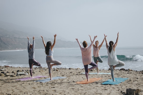 people doing yoga at the beach